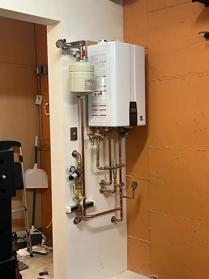 Plumbing technician inspecting water heater connections in Manor
